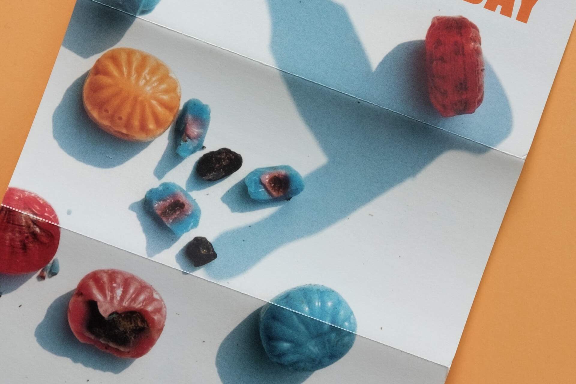 Detailfoto. Bonbons und Schatten eines Hammers bilden das Flyer-/Plakat-Motiv für die Auktion mit Falkenberg im Kunsthaus.
